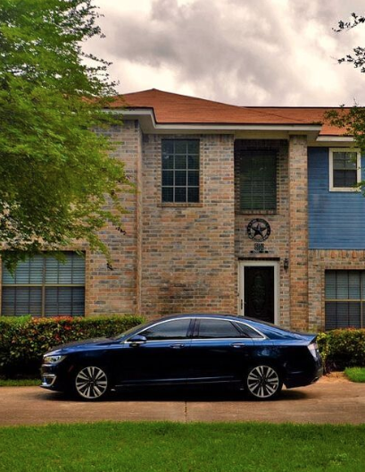 A dark blue Lincoln sits outside a brick home in the driveway in Columbus GA.