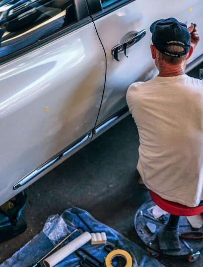 A window tint removal specialist works on taking the tint off an older vehicle.