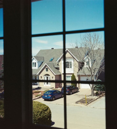 A view from inside a home looking through tint material to the outside street and houses.