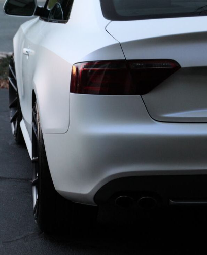 A close up photo of a white car with dark tinted taillights.